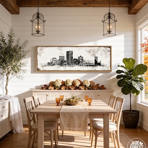 a cozy dining room with a wooden table and chairs, a large framed city skyline artwork on the wall, and various decorative elements such as potted plants and vases.
