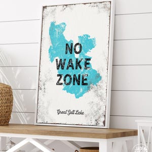 The No Wake Zone with a dusty blue lake silhouette print displayed above a small white bench.