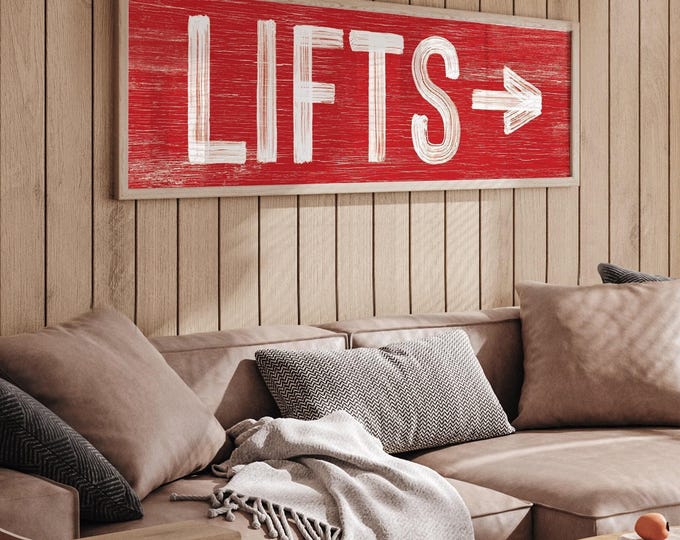 Rustic directional sign pointing to the lifts in red and white