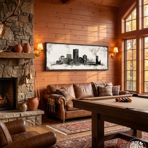 a cozy living room with a fireplace, a large window, and a framed artwork of a city skyline hanging on the wall. The room is furnished with a leather sofa, a pool table, and a fireplace with a stone mantel. The overall atmosphere of the room is warm and inviting, with a harmonious blend of rustic and modern elements.