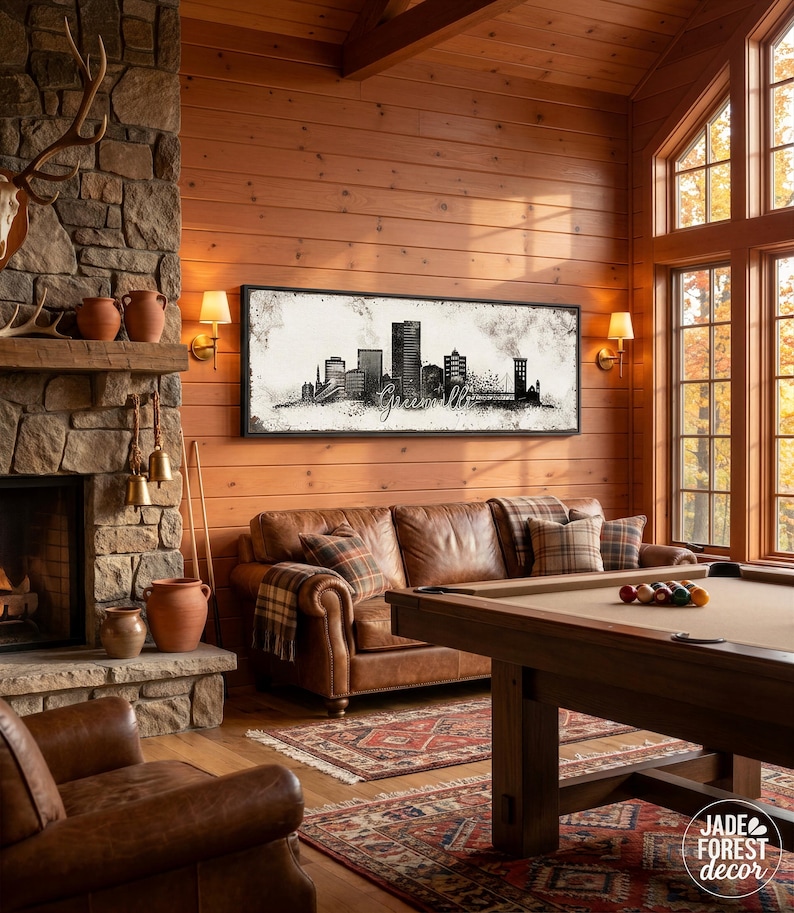 a cozy living room with a fireplace, a large window, and a framed artwork of a city skyline hanging on the wall. The room is furnished with a leather sofa, a pool table, and a fireplace with a stone mantel. The overall atmosphere of the room is warm and inviting, with a harmonious blend of rustic and modern elements.