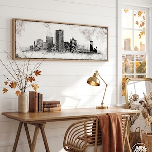 a cozy workspace with a wooden desk, a lamp, a mirror, and a framed cityscape artwork on the wall. The desk is adorned with books and a vase of flowers, creating a pleasant and inviting atmosphere.