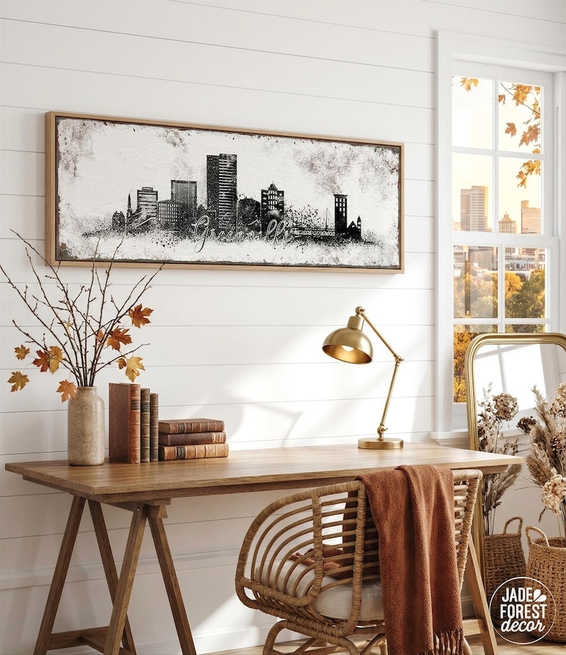 a cozy workspace with a wooden desk, a lamp, a mirror, and a framed cityscape artwork on the wall. The desk is adorned with books and a vase of flowers, creating a pleasant and inviting atmosphere.