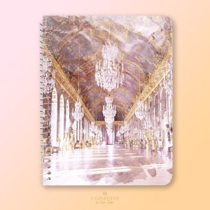May include: Spiral-bound notebook featuring a watercolor image of a grand hall with ornate chandeliers and gold accents. The notebook cover displays the text "CASTLEFIELD" in gold lettering.