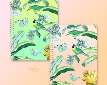 Puede incluir: Dos cuadernos de espiral con un tema tropical. Los cuadernos tienen un fondo degradado verde y rosa con ilustraciones de pájaros, mariposas y plantas de plátano. El texto "CASTLEFIELD" está impreso en la portada del cuaderno verde.