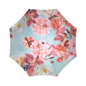 May include: A blue umbrella with a floral print featuring pink, red, and white flowers. The umbrella is closed and the handle is not visible.