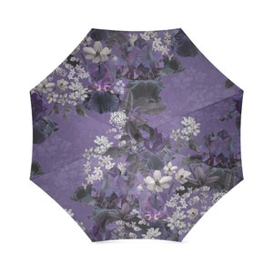 May include: Purple umbrella with a floral pattern featuring white and purple flowers. The flowers are arranged in a repeating pattern on a purple background.