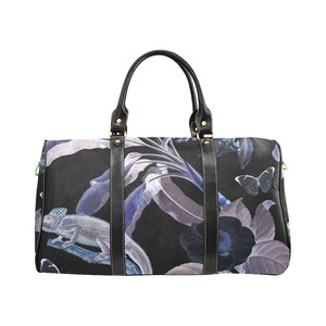 May include: Black duffel bag with a floral print featuring butterflies, leaves, and a chameleon. The print is in shades of blue, purple, and white on a black background.