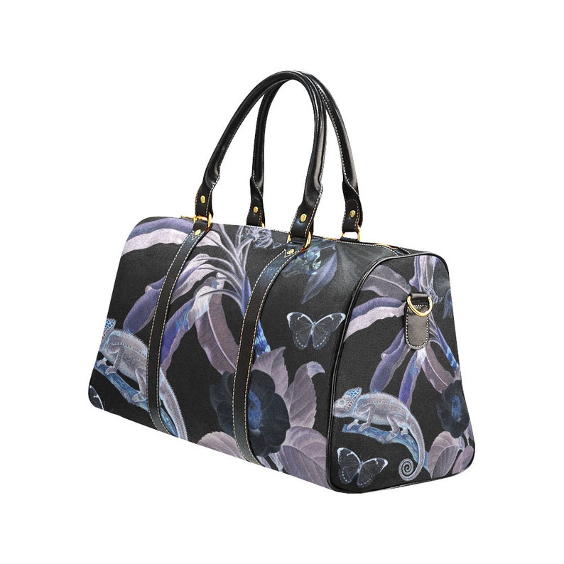 May include: Black travel bag with a floral print featuring butterflies and chameleons. The bag has black leather handles and gold accents.