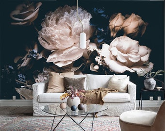 May include: A wall mural featuring large, pale pink peony flowers against a dark navy blue background. The mural is positioned behind a white sofa with beige and brown throw pillows, a glass coffee table, and a beige upholstered armchair.