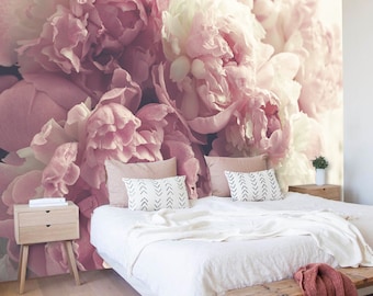 May include: A large-scale wall mural featuring a close-up of soft pink and white peony flowers. The mural covers the entire wall behind a bed with white bedding, two light wood nightstands, and a wooden bench at the foot of the bed.