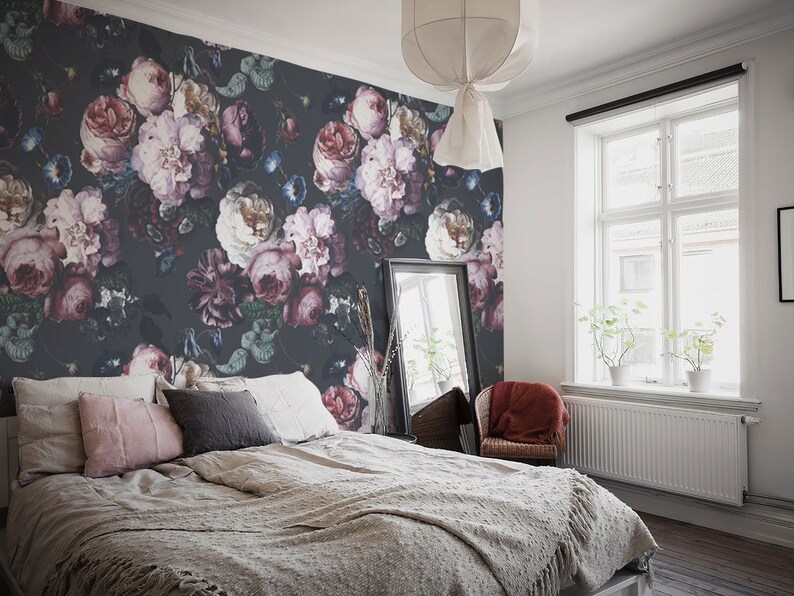 May include: A bedroom featuring a dark charcoal wallpaper with a large-scale floral pattern in shades of pink, white, and deep purple. The bed is dressed in neutral beige bedding with pink and gray accent pillows, positioned against the floral wall.