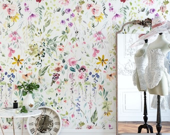 Könnte beinhalten: Tapete mit einem Aquarell-Blumenmuster mit rosa, gelben, violetten und grünen botanischen Elementen auf weißem Hintergrund. Die Szene umfasst einen Tisch mit Marmorplatte, eine runde Uhr und eine Schaufensterpuppe in weißer Spitzenkleidung.