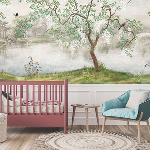 May include: A room interior featuring a dark pink cot, a light blue armchair with a white cushion, a small wooden side table, and a woven basket. The wall is covered in a mural depicting a landscape with a lake, a tree, and birds.