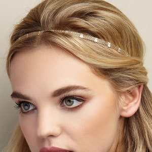 May include: A woman with long blonde hair wearing a green ruffled blouse and a gold headband.