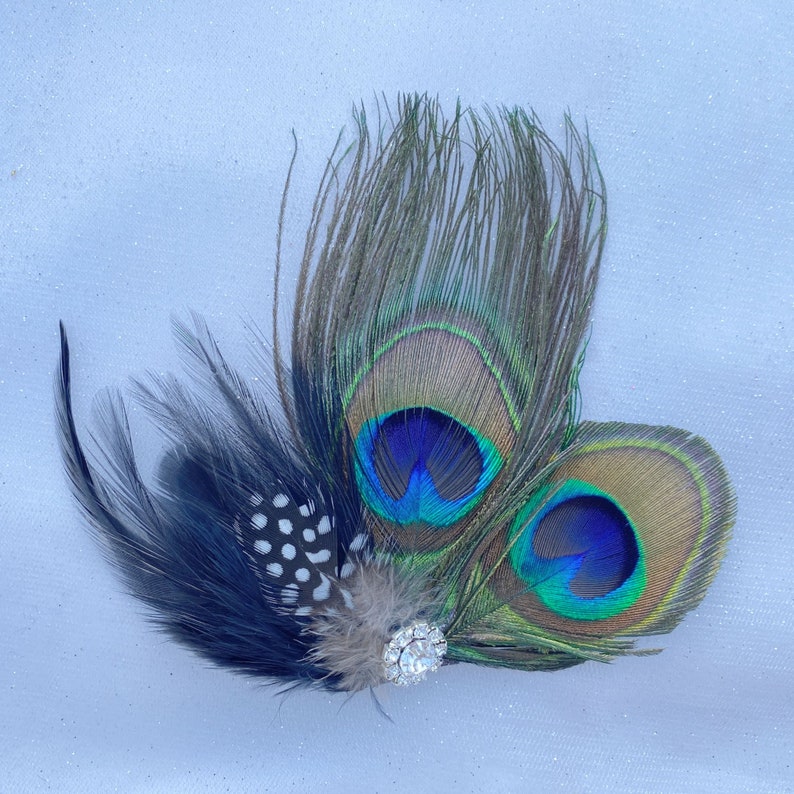 May include: A peacock feather hair clip with a black and white feather accent and a sparkly rhinestone embellishment.