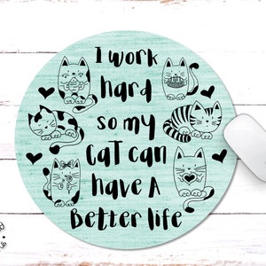 May include: A light blue round mouse pad with a white background and black text that reads "I work hard so my cat can have a better life". There are six black and white illustrations of cats on the mouse pad.