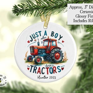 May include: A white ceramic ornament with a red and blue tractor illustration. Text reads "Just a boy who loves tractors" and "Hunter 2025". The ornament is approximately 3" in diameter and has a glossy finish with a ribbon for hanging.