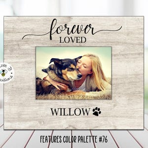 May include: A wooden picture frame with a whitewashed finish. The frame has a photo insert with a woman and a dog. The text "forever loved" is written above the photo insert. The text "WILLOW" is written below the photo insert with a paw print symbol. The text "FEATURES COLOR PALETTE #76" is written below the frame.
