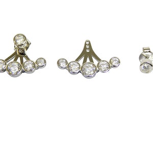 May include: A pair of silver earrings with a row of five clear cubic zirconia stones. The earrings are designed to be worn on the upper ear, with a small post that goes through the earlobe and a larger piece that sits on the upper ear.