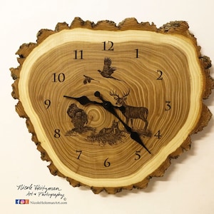 May include: A wooden clock with a natural wood finish and a wood grain pattern. The clock face features a deer, a turkey, and a pheasant, all engraved in the wood. The clock hands are black and the numbers are in a simple font.