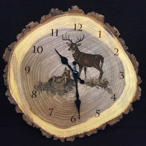 May include: A rustic wooden clock with a tree bark design. The clock face features a laser-etched image of a buck and a fawn with Roman numeral hour markers. The clock hands are black.
