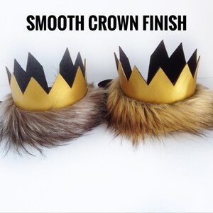 May include: Two gold crowns with black felt points and a faux fur trim. The text "SMOOTH CROWN FINISH" is at the top of the image.