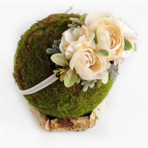 May include: A white floral headband with a moss base and birch bark accents. The headband is decorated with ivory roses and greenery.