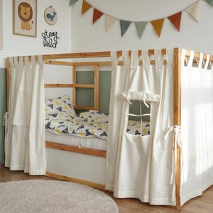 May include: A wooden bed frame with white curtains and a window. The bed has a mattress with a patterned comforter and pillows. The room is decorated with a world map, a lion picture, and a garland of colorful flags.