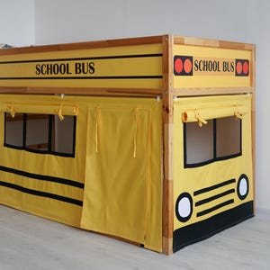 Könnte beinhalten: Ein gelb-schwarzes Schulbus-Themenbettgestell mit dem Aufdruck "SCHOOL BUS" auf der Vorderseite. Das Bett hat einen Holzrahmen und gelbe Vorhänge mit schwarzen Akzenten. Die Vorderseite des Bettes hat ein busähnliches Design.