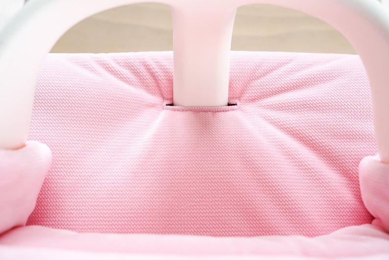 Op de afbeelding: Close-up van een roze stoffen stoelkussen met een wit frame. De stof heeft een textuurpatroon.