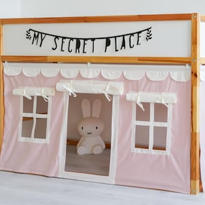 May include: A wooden bunk bed with a pink tent-like canopy. The canopy has white scalloped trim and two white windows. The bed has a shelf on the side and a banner that reads "My Secret Place".