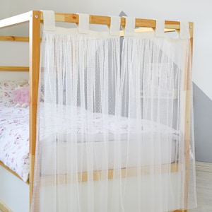 May include: A set of two white sheer curtains with a dotted pattern, hanging from a wooden bed frame. The curtains are labeled "SHORT SIDE (2PC)".