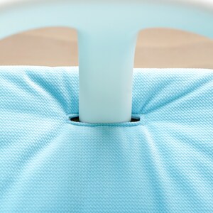 Pu&ograve; includere: Primo piano di una sedia in tessuto blu chiaro con una struttura in plastica bianca. Il tessuto ha una trama testurizzata.