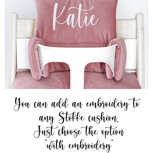Pu&ograve; includere: Un cuscino rosa per seggiolone con un nome ricamato in bianco "Katie". Puoi aggiungere un ricamo a qualsiasi cuscino Stokke. Basta scegliere l'opzione "con ricamo".