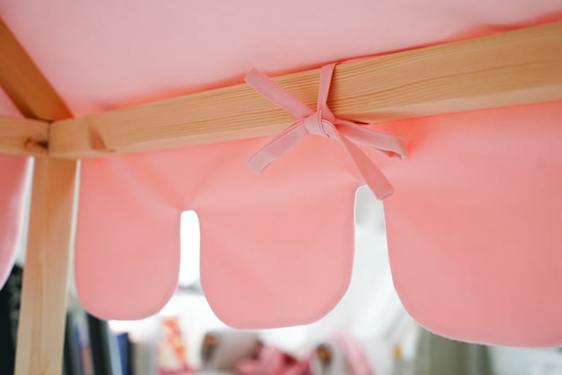 K&ouml;nnte beinhalten: Ein rosa Stoffbaldachin mit gewellten R&auml;ndern ist an einem Holzrahmen befestigt. Der Stoff ist in der Mitte mit einer Schleife gebunden.