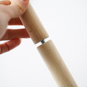 Puede incluir: Dos clavijas de madera con un tornillo de metal que las conecta. Las clavijas son de color marr&oacute;n claro y tienen un acabado liso.