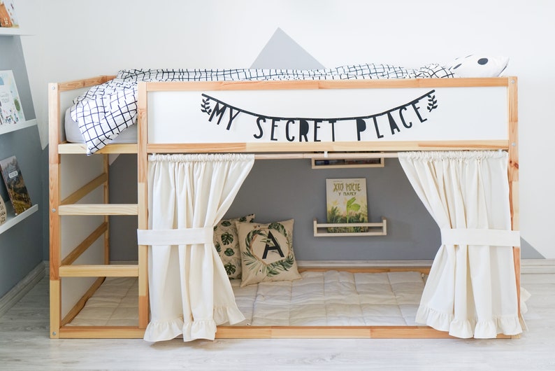 Puede incluir: Una litera de madera con una cabecera blanca y un dosel de tela blanca. La cabecera tiene una pancarta negra que dice "My Secret Place". La cama tiene un edred&oacute;n a cuadros blanco y negro y una almohada blanca.