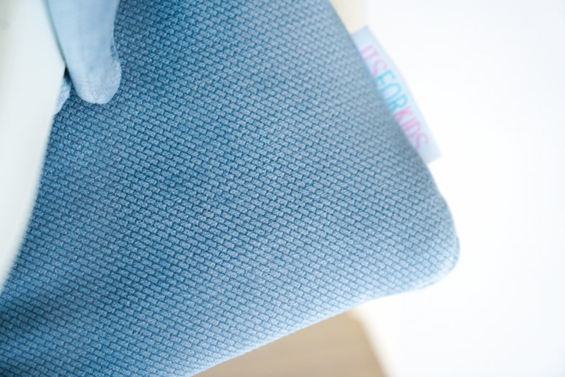 May include: Close-up of a blue fabric with a textured weave. A white tag with the text "ITS FOR KIDS" is attached to the fabric. The fabric is a solid light blue color.