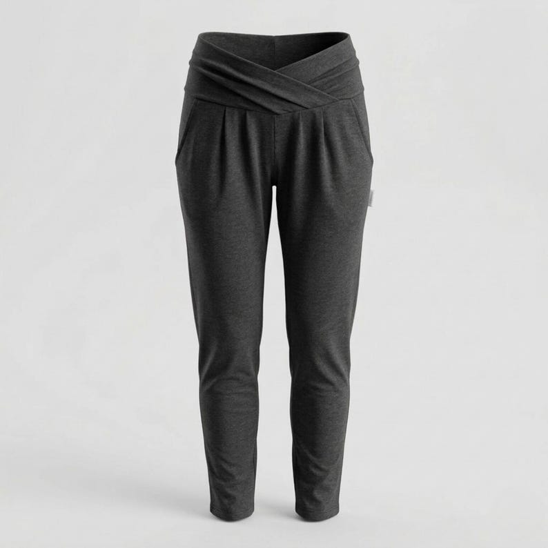 May include: Dark gray women's pants with a unique crossover waistband design. These casual pants feature a relaxed fit with pockets and a tapered leg. The fabric appears to be a soft, comfortable material, suitable for everyday wear.