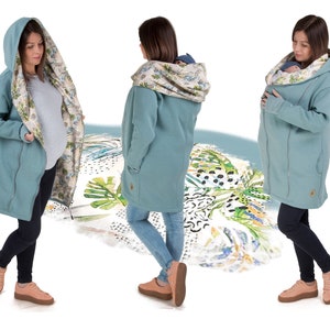 Könnte beinhalten: Eine tealfarbene Kapuzenjacke mit einem floralen Futter. Die Jacke hat eine Kängurutasche und einen Reißverschluss. Das Model trägt die Jacke mit Jeans und Sneakers.