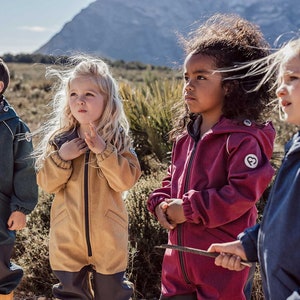 Könnte beinhalten: Vier Kinder tragen Kapuzen-Oberbekleidung mit Reißverschluss in verschiedenen Farben: Blaugrün, Beige, Burgunderrot und Marineblau. Die Jacken haben ein herzförmiges Logo auf dem Ärmel. Sie stehen im Freien in einer natürlichen Umgebung.