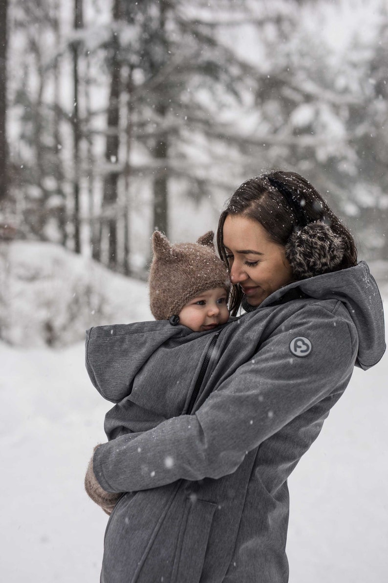 maman sous la neige avec un manteau de portage grossesse