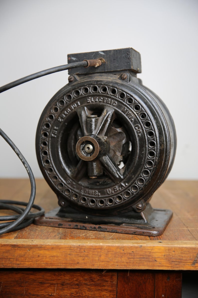 May include: A black cast iron electric motor with a cord and plug. The motor has a round shape with a central hub and spokes. The text "The Paragon Electric Mfg. Co. St. Louis, U.S.A." is inscribed on the motor.