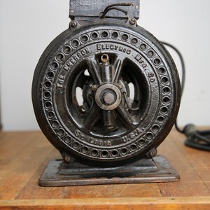 May include: A black cast iron electric motor with the text "The Emerson Electric Mfg. Co. St. Louis U.S.A." on the front.