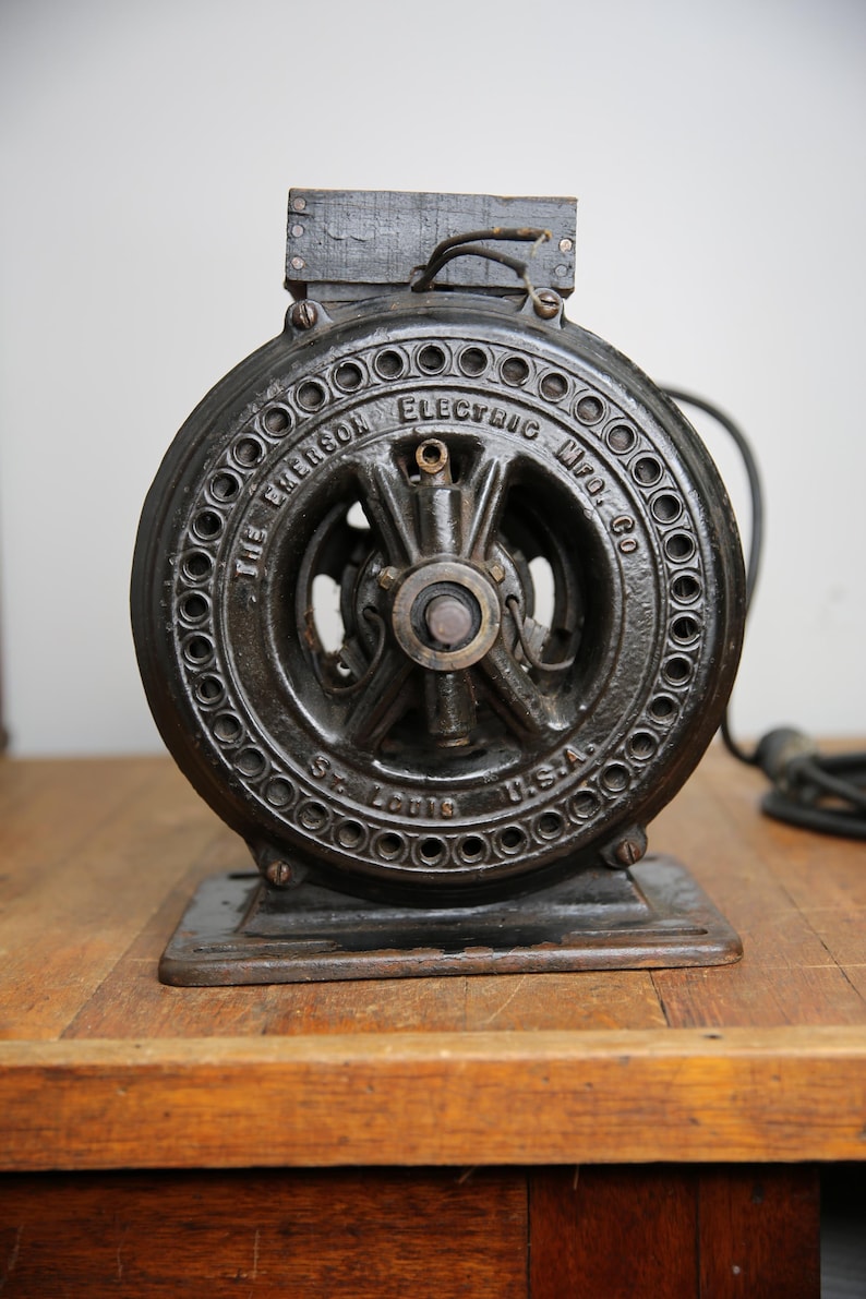 May include: A black cast iron electric motor with the text "The Emerson Electric Mfg. Co. St. Louis U.S.A." on the front.