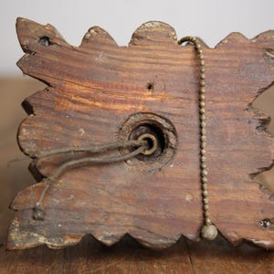 Puede incluir: Primer plano de la parte posterior de una l&aacute;mpara de madera con un dise&ntilde;o decorativo y ornamentado. La l&aacute;mpara tiene una cadena de tracci&oacute;n y un agujero para el cableado.