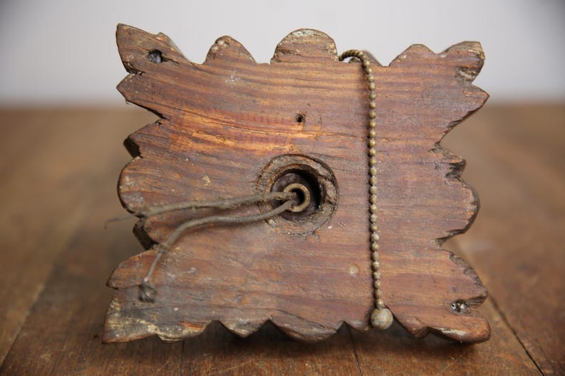 Puede incluir: Primer plano de la parte posterior de una l&aacute;mpara de madera con un dise&ntilde;o decorativo y ornamentado. La l&aacute;mpara tiene una cadena de tracci&oacute;n y un agujero para el cableado.