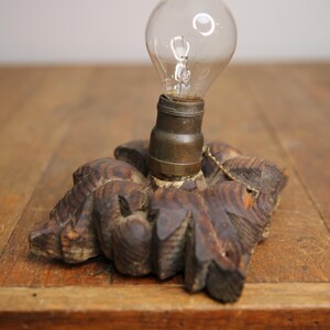 Puede incluir: Una base de l&aacute;mpara de madera vintage con un dise&ntilde;o tallado y una bombilla de vidrio transparente.