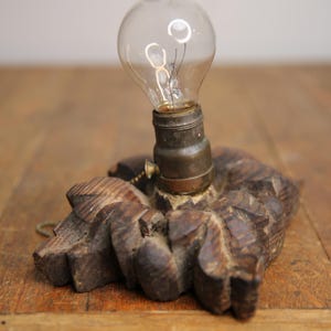 Puede incluir: Una base de l&aacute;mpara de madera vintage con un dise&ntilde;o tallado y una bombilla de vidrio transparente.